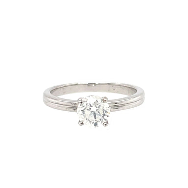 An 18ct white gold diamond solitaire engagement ring with a round brilliant cut diamond mounted in a four claw setting, extending to a 2mm wide band.